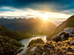 Wschód słońca, Wyspa Południowa, Nowa Zelandia, Promienie słońca, Chmury, Góry, Park Narodowy Fiordland, Jezioro